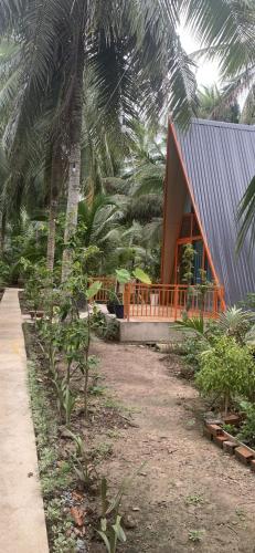 a house with a palm tree in front of it at Homestay and Tour Ben Tre in Ben Tre