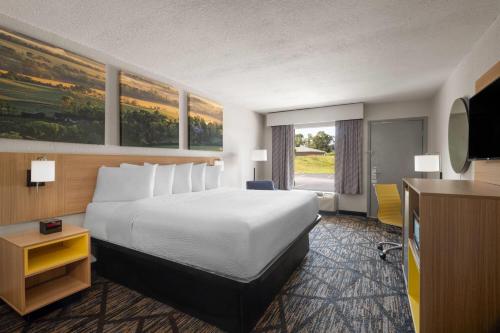 a hotel room with a bed and a television at Days Inn by Wyndham Augusta Wheeler Road in Augusta