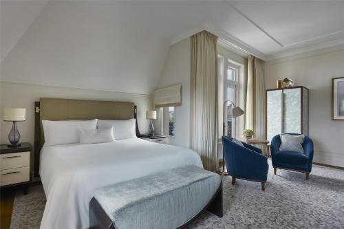 a bedroom with a large white bed and a blue chair at Waldorf Astoria Amsterdam in Amsterdam