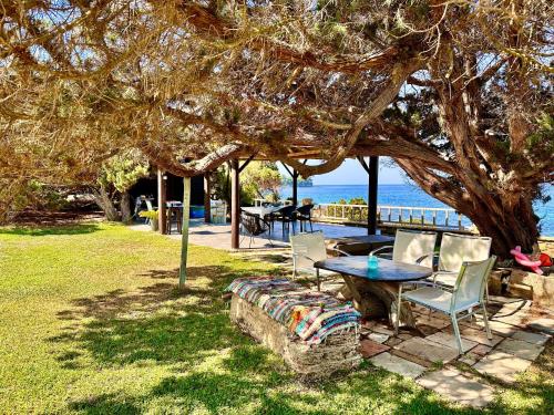 a picnic table and chairs under a tree near the ocean at Genari Beach Apartments -Family sea view apartment in Korakokhórion
