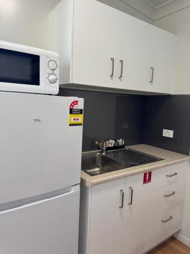 a white kitchen with a sink and a microwave at Bowen Holiday Park in Bowen