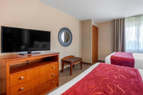 a hotel room with a flat screen tv and a bedroom at Comfort Suites North Dallas in Dallas