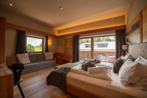 a bedroom with a large bed and a couch at Berghotel Zorzi in Alpe di Siusi