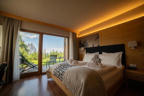 a bedroom with a large bed and a large window at Berghotel Zorzi in Alpe di Siusi