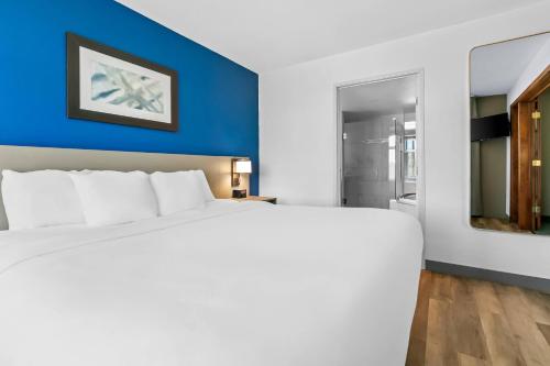 a large white bed in a room with a blue wall at Comfort Inn & Suites Grand Blanc-Flint in Grand Blanc