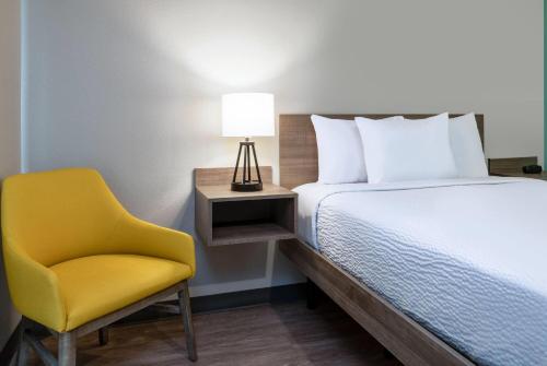 a bedroom with a bed and a yellow chair at ECHO Suites Extended Stay by Wyndham Houston Pasadena Fwy Pl in Pasadena