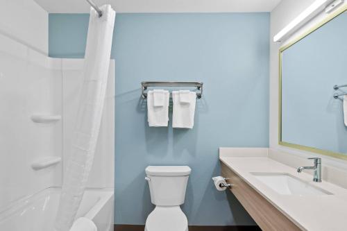 a bathroom with a toilet and a sink and a mirror at WoodSpring Suites Richmond Airport in Henrico
