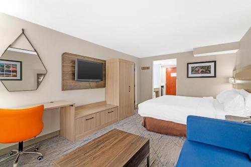 a hotel room with a bed and a desk and a tv at Keene Elm City Hotel, an Ascend Collection Hotel in Keene