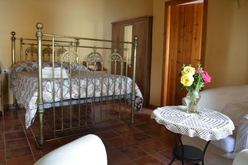 a bedroom with a bed and a table with a vase of flowers at Casa Rural FuenteVieja in La Mata de los Olmos