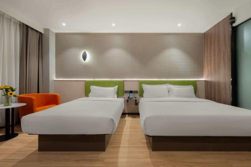 a room with two beds and a chair at Rezen Select Hotel (Guangzhou Keyun Road Financial City) in Guangzhou