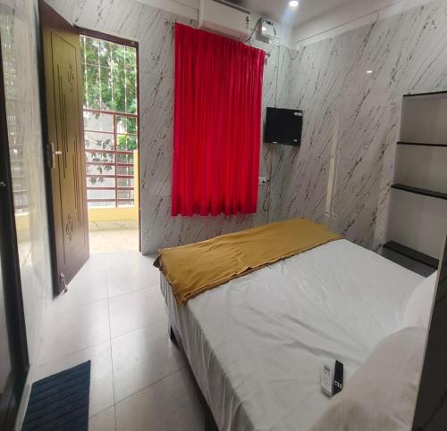 a bedroom with a bed with a red curtain and a window at Sun Shine Guest House in Puducherry