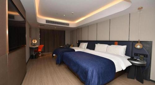 a bedroom with a large bed with a blue blanket at Yitel Collection Lianyungang High-speed Railway Station Suning Plaza in Lianyungang