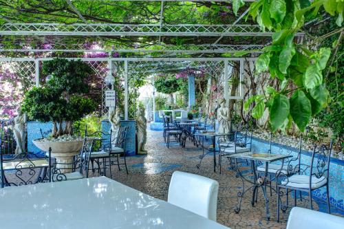 a restaurant with tables and chairs under a pergola at Lloyd's Baia Hotel in Vietri sul Mare