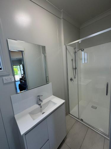 a white bathroom with a sink and a shower at Bowen Holiday Park in Bowen
