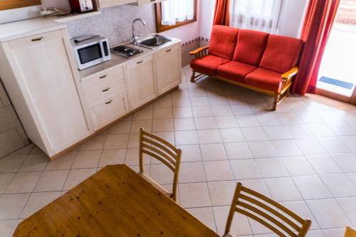 a kitchen with a table and a red chair and a couch at Agriturismo Dai Gobbi in Fara Vicentino