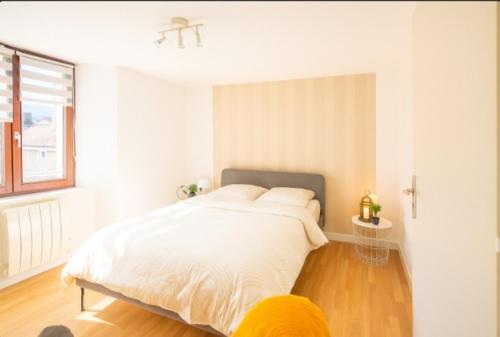 a white bedroom with a large bed and a window at Les remparts in Ensisheim