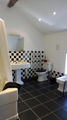 La salle de bains est pourvue d'un sol en damier noir et blanc. dans l'établissement Val de Costes, à Saint-Maurin