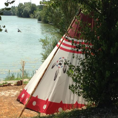 a red and white tent next to a river at Zagreb Camp Bungalows in Rakitje
