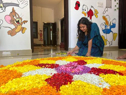 a woman standing in front of a large flower arrangement at Yes Hostel Varkala - Black Beach Road in Varkala