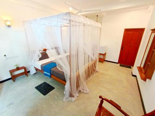 a bedroom with a canopy bed with white curtains at Minuda Villa in Kamburugamuwa