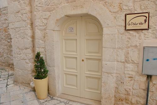 a white door in a stone building with a potted plant at La Dolce Vite in Turi