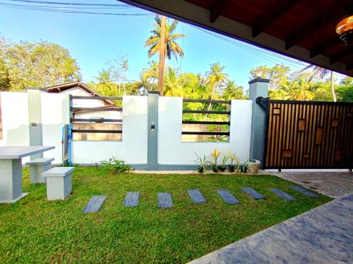 a backyard with a white fence and a table and grass at Minuda Villa in Kamburugamuwa