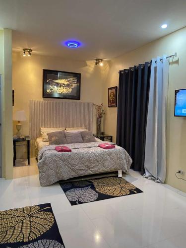 a bedroom with a bed and a tv and curtains at Precious Ruby's Apartment in Manila