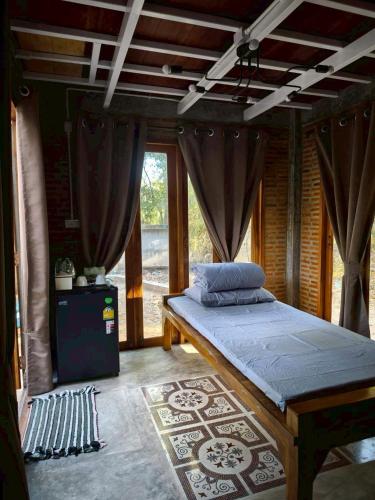 a bedroom with a bed with curtains and a rug at Phawaeng Resort พะแวงรีสอร์ท in Ban Noen Sabok