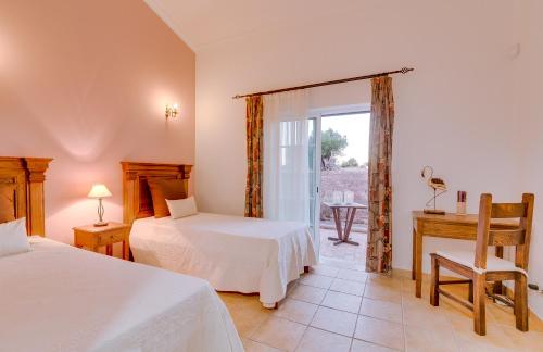a bedroom with two beds and a desk and a window at Espargosa Monte de Baixo & Art in Castro Marim