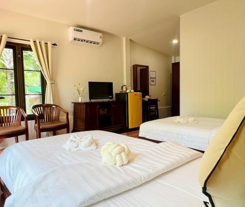 a hotel room with two beds with towels on them at Baan Varintorn Suanphueng in Suan Phung