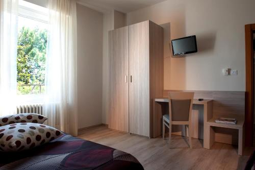 a bedroom with a desk and a table with a television at Albergo Valentina in Peschiera del Garda