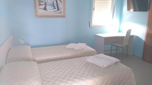 een slaapkamer met 2 bedden, een bureau en een tafel bij Pensione Afrodite in Metaponto