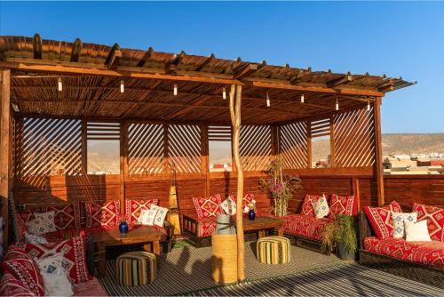 a pavilion with couches and tables on a patio at Aourir Waves Surf House in Aourir