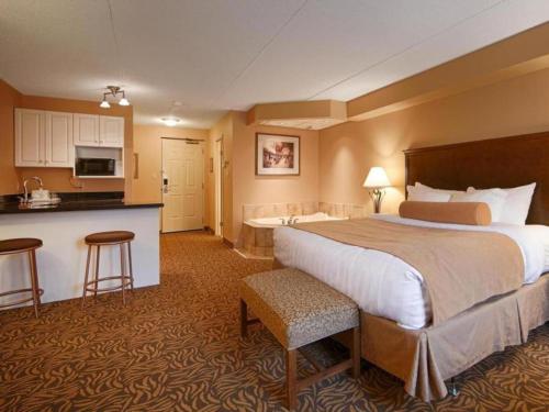 a hotel room with a large bed and a kitchen at Best Western Plus Orillia Hotel in Orillia