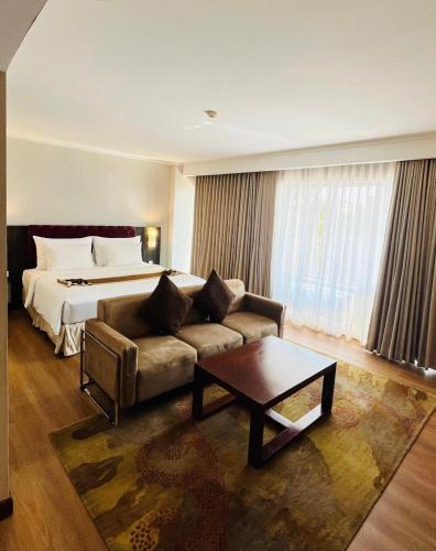 a hotel room with a bed and a couch and a table at Vrata Hotel Yogyakarta in Kalasan