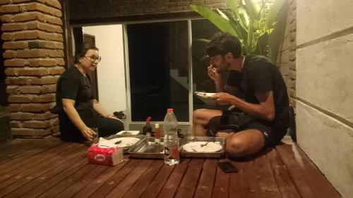 a man sitting on the floor eating a plate of food at Lentera Lombok in Tetebatu