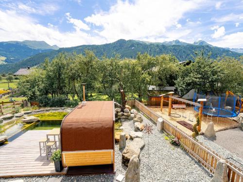 a backyard with a wooden deck and a playground at Farmhouse in Bramberg with Natural Pond in Dorf