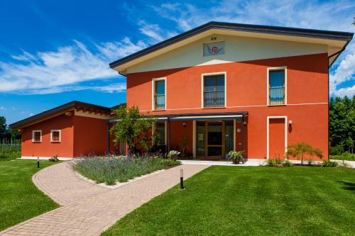 a red building with a green lawn in front of it at Agriturismo la Chiocciola in Sacile