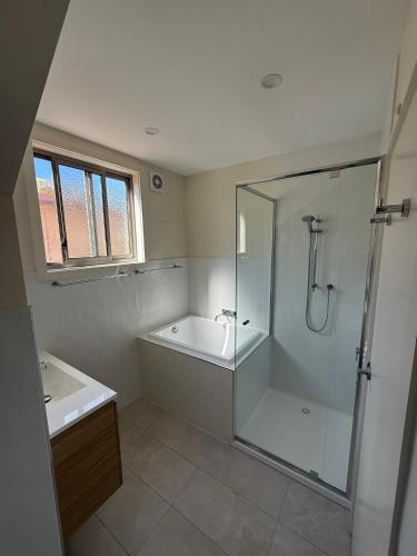a bathroom with a shower and a tub and a sink at Golden Mile - On the Waterfront in Bundalong
