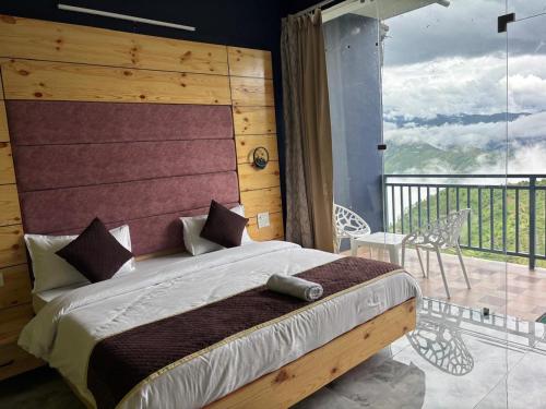 une chambre avec un grand lit et un balcon dans l'établissement The Happy Land Mussoorie, à Mussoorie