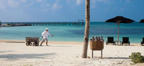 a man walking along a beach with a surfboard at Nizuc Resort & Spa in Cancún