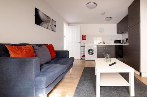 a living room with a blue couch and a white table at Town Centre Apartment with FREE Parking in Loughborough