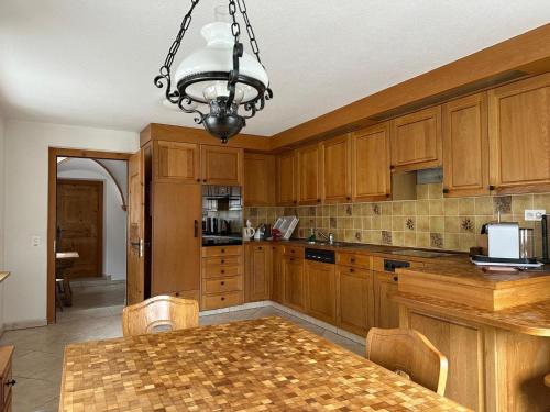 a kitchen with wooden cabinets and a table and a chandelier at Chasa pin in Müstair