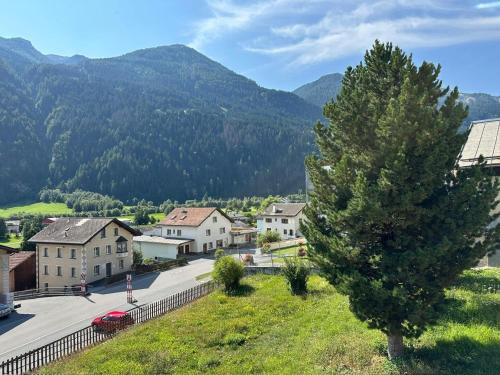 a town with a tree and mountains in the background at Chasa pin in Müstair
