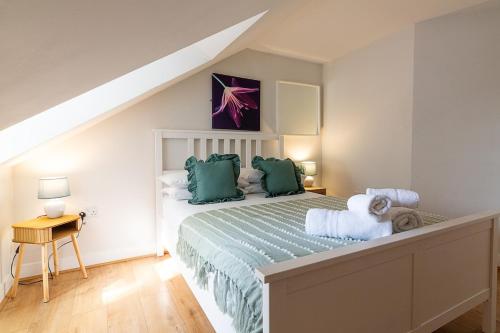 a bedroom with a large bed with green pillows at Town Centre Apartment with FREE Parking in Loughborough