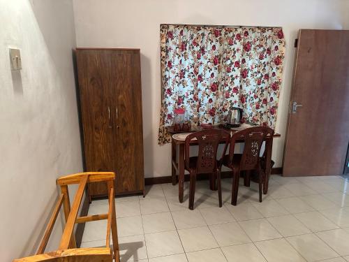 a dining room with a table and chairs and a curtain at Mango Tree Budget Home Stay in Homagama