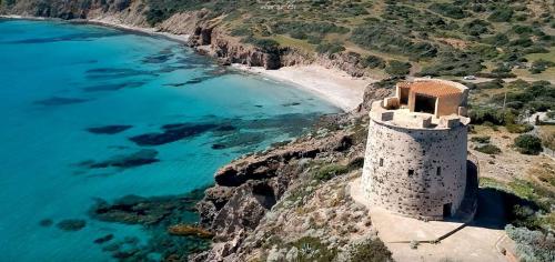a tower on a cliff next to a beach at Charming SantAntioco Apt with 2-Way Air Con in SantʼAntìoco