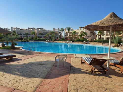 a swimming pool with two chairs and an umbrella at jo sunny lakes in Sharm El Sheikh