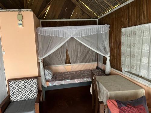 une petite pièce avec un lit et une table dans l'établissement Le Rocher, sur l'île Sainte-Marie