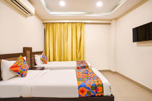 two beds in a hotel room with a television at FabHotel Millennium Suites in Bengaluru